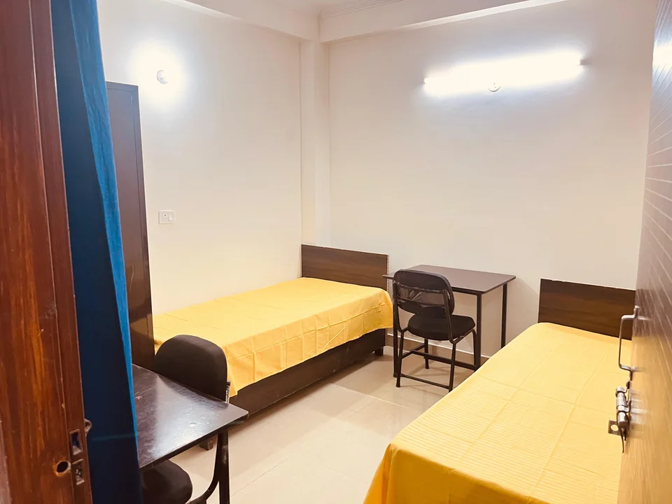 Two beds and study desks in a furnished Kings Hostel room.